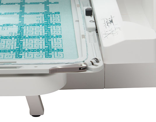 Close-up of the hoop attachment clamp on the Janome 550e, showing the magnetic clamp system and hoop connection point