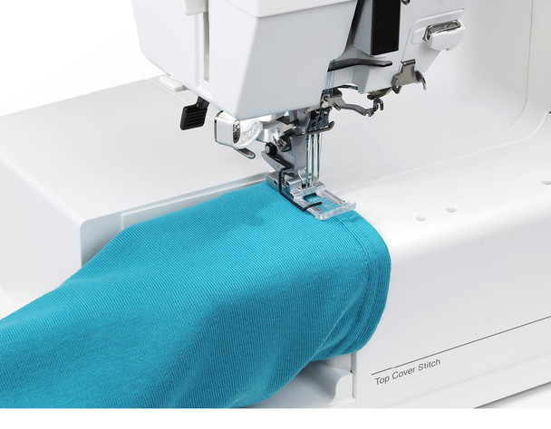 The machine with the flat bed removed, demonstrating the free-arm configuration. A teal knit tube (like a sleeve or legging) is being fed through the open arm area. "CoverPro 3000 Professional" branding and the FINE/STD switch are visible. Great for showcasing the free-arm capability.