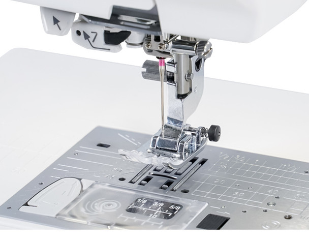 Close-up of the Janome MC9410 QC needle plate area showing the straight stitch plate, 9mm width markings, and 7-piece feed dog