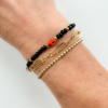 wearing black onyx gemstone with two orange skull beads with simple chain link bracelet and gold ball beaded bracelet