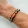 wearing square hematite gemstones bracelet with orange turquoise skull beads and gold ball beaded bracelet