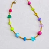 Beaded necklace with an open lobster clasp laid on a white surface, showing gold-tone beads with smiley faces, translucent stars, and glossy colorful stones.
