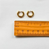 baby gold huggie hoops next to ruler for size