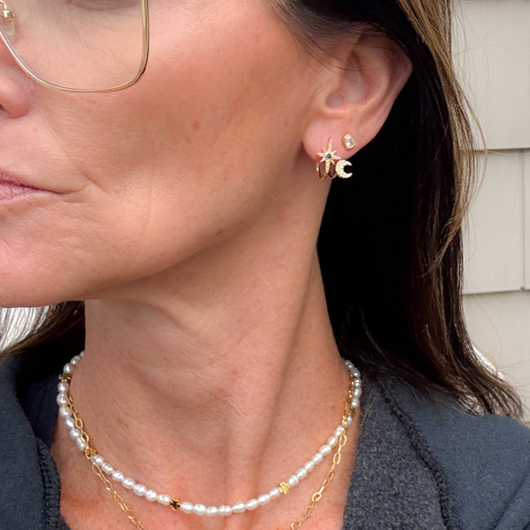 wearing cosmic moon and star studs with tiny clover pearl necklace