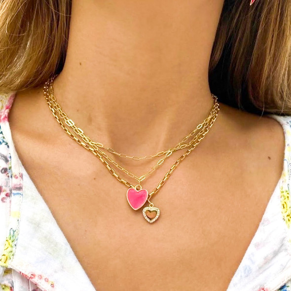 wearing  pink statement heart enamel pendant necklace layered with gold heart necklace