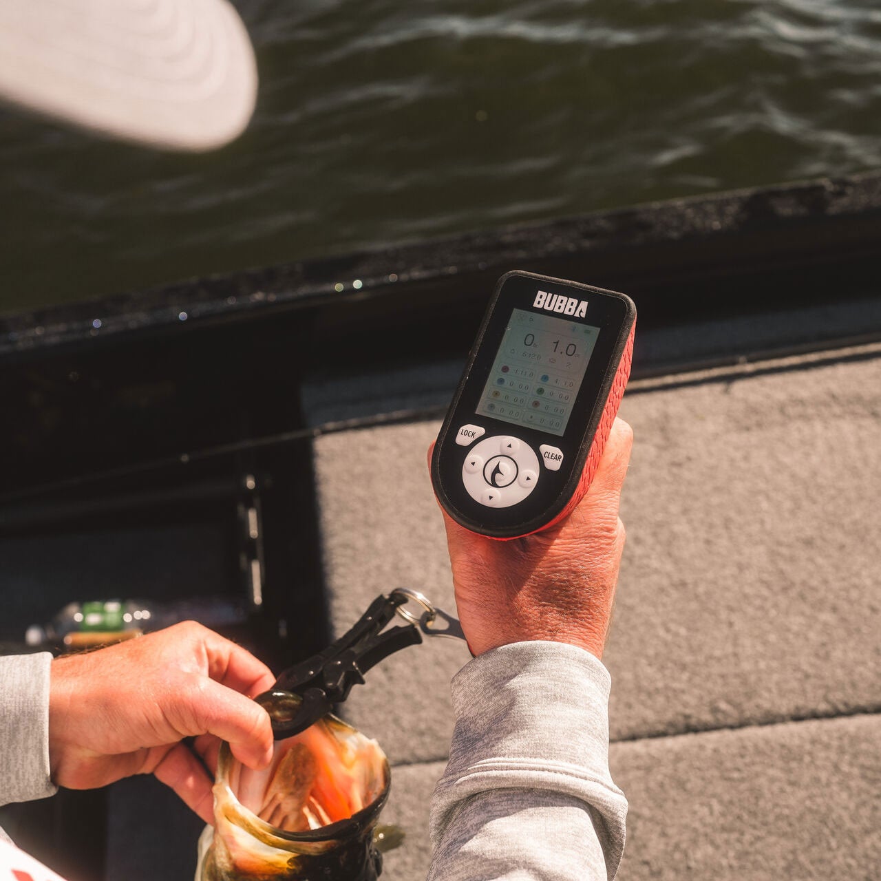 Angler weighing a largemouth bass using the lip grip that comes with the handheld Bubba Blade Pro Series Smart Fish Scale