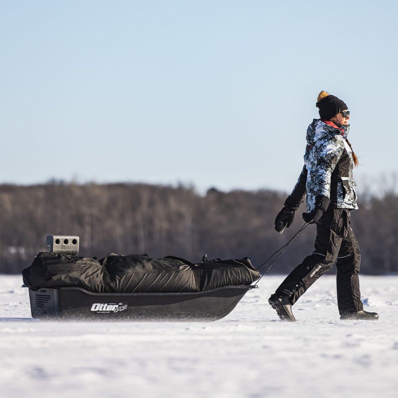 Angler pulling an Otter Outdoors Sport Sled on the ice