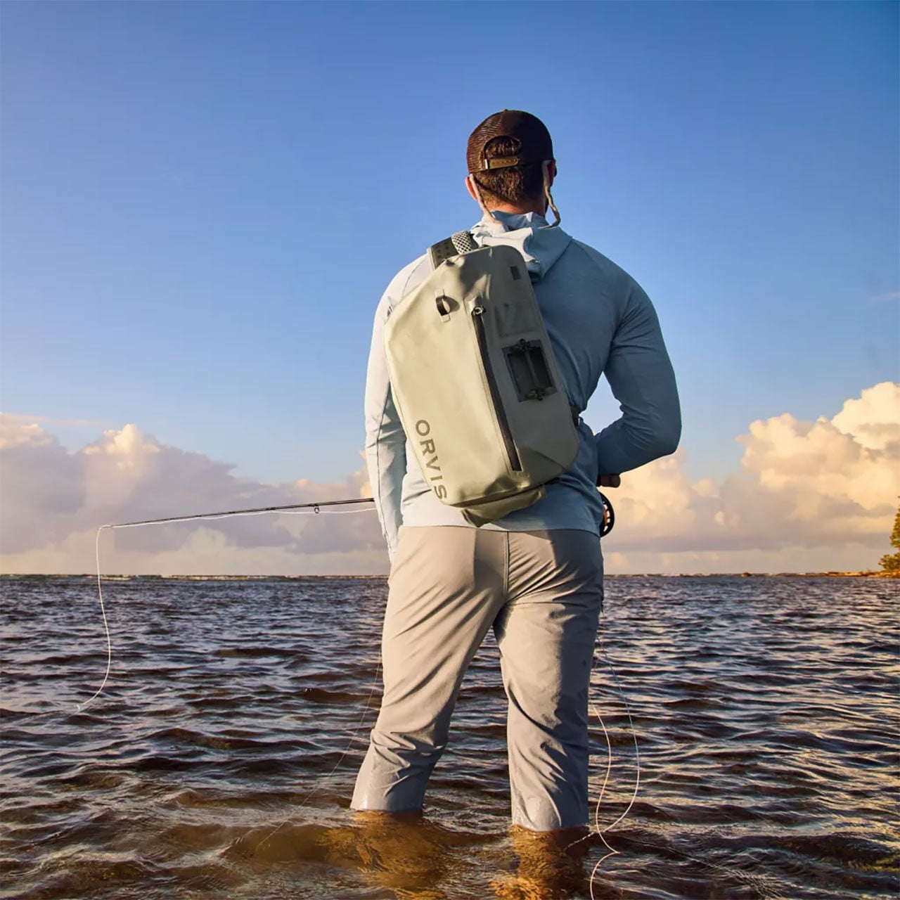 Orvis PRO Waterproof Backpack worn by male fly fishing angler standing calf-deep in a lake