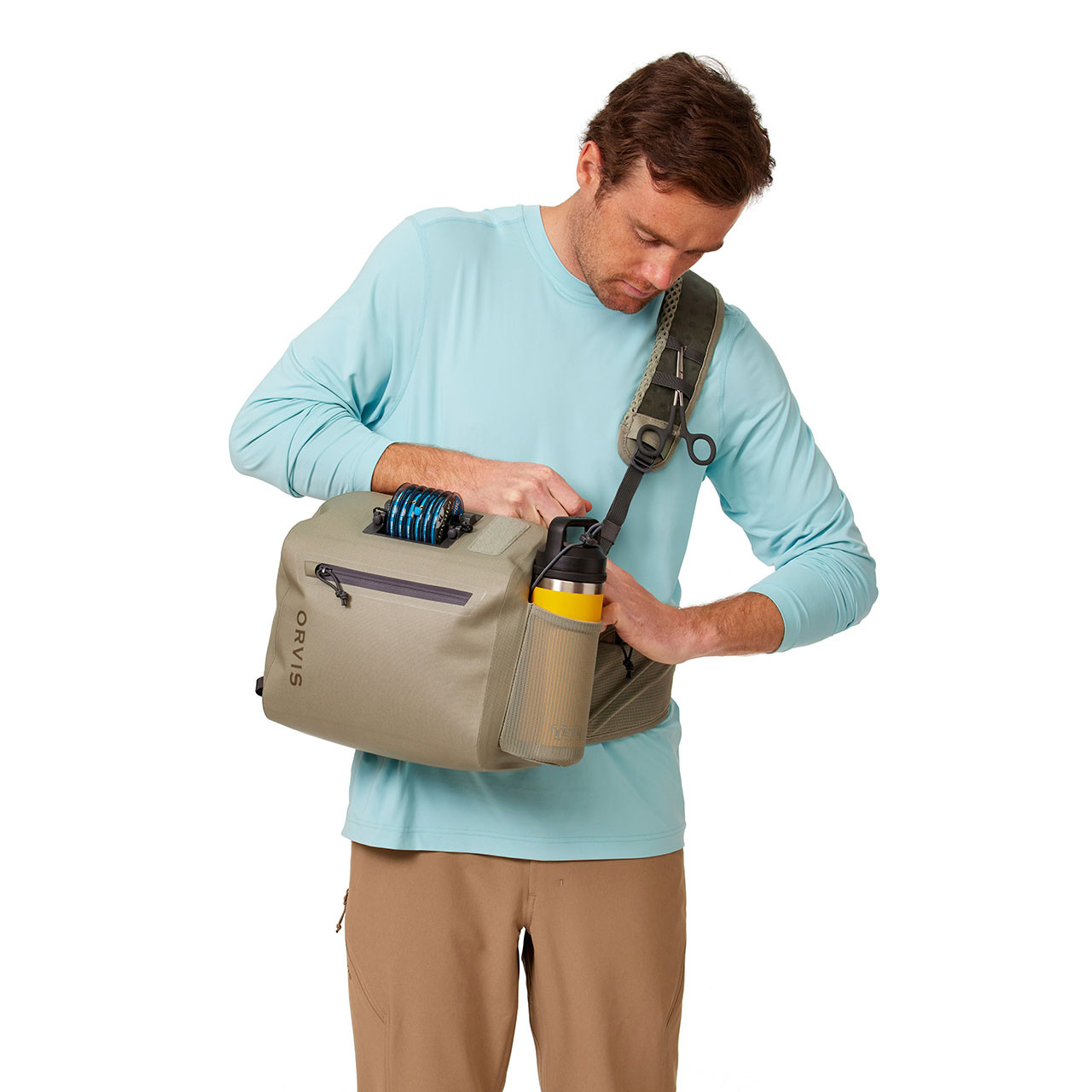 Orvis PRO Waterproof Hip Pack on male model accessing main compartment from his front (accessories not included)