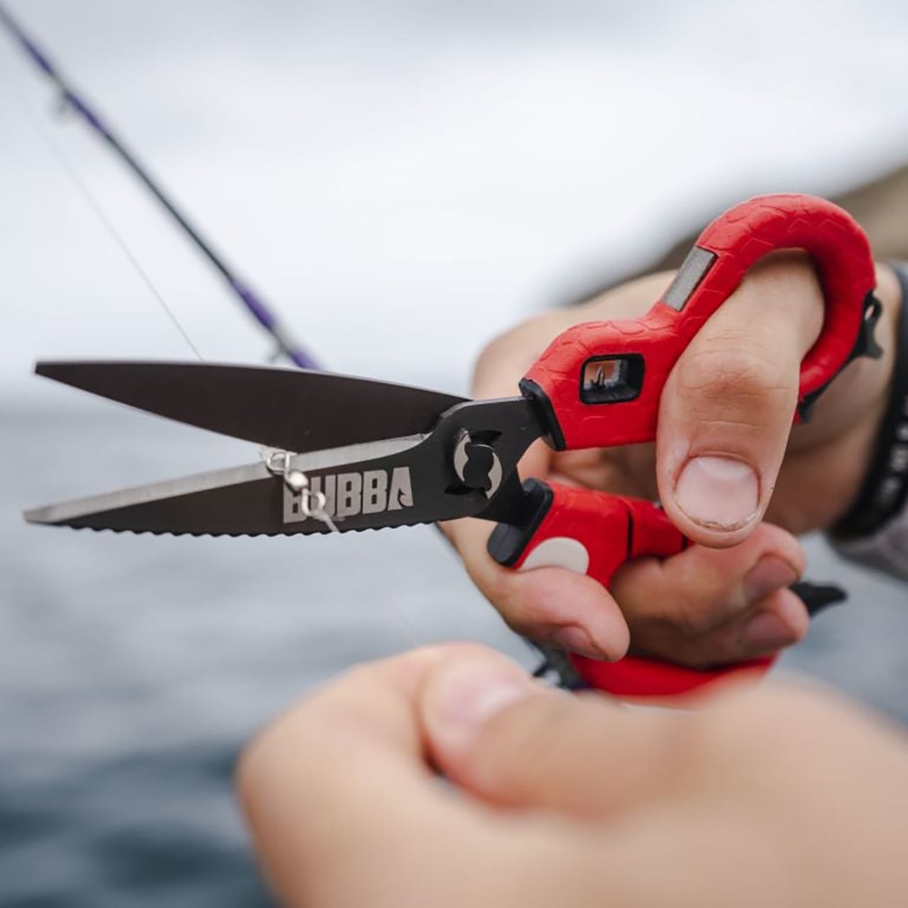 Bubba Blade Medium Shears red handle in hand cutting fishing line