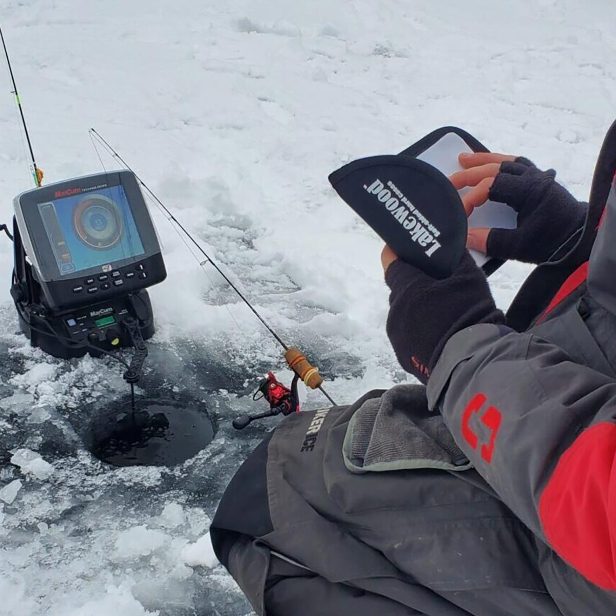 Lakewood Lure Wallet held open by an ice fishing angler choosing lures next to ice hole