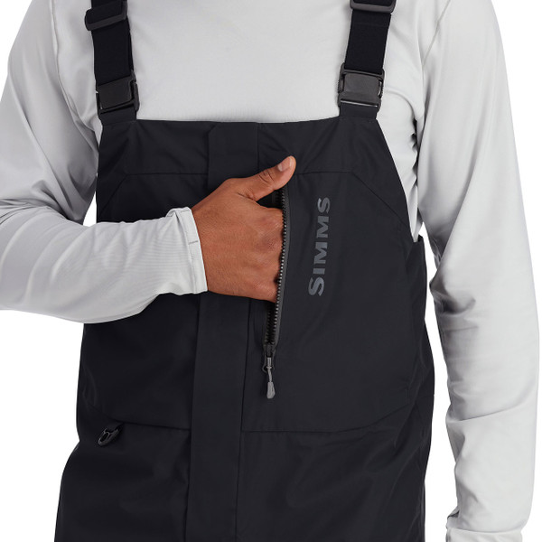 Simms Men's Challenger Fishing Bib Black color with model displaying zippered chest pocket