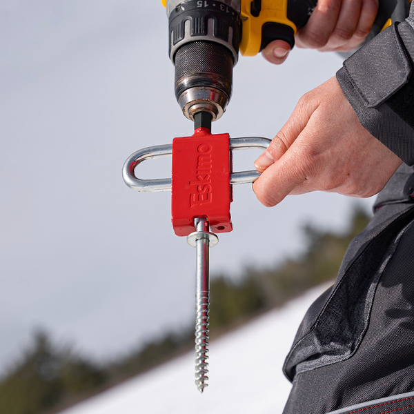 Close up of  angler holding Eskimo Ice Anchor Drill Adapter inserted into drill with ice anchor attached