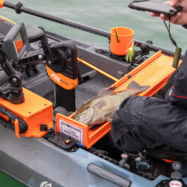 Kayak angler taking a photo of fish that's placed on a YakAttack LeaderBoard measuring board