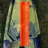 Close up of orange YakAttack LeaderBoard placed lengthwise on a kayak that's resting on grass