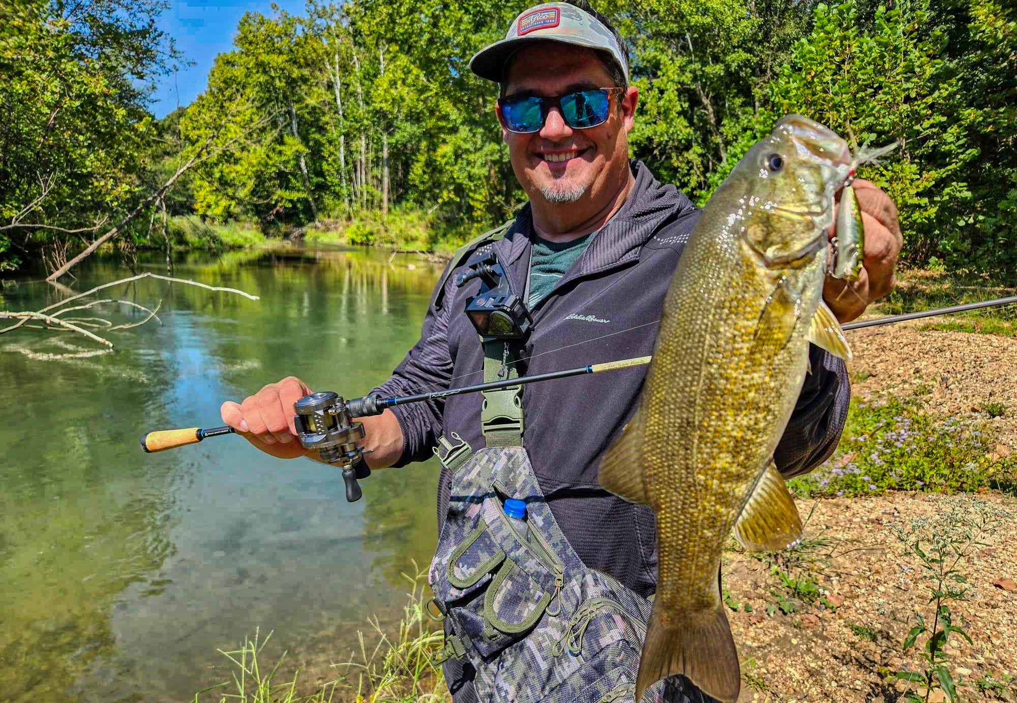 Angler fishing a small creek for bass, targeting a rocky current break