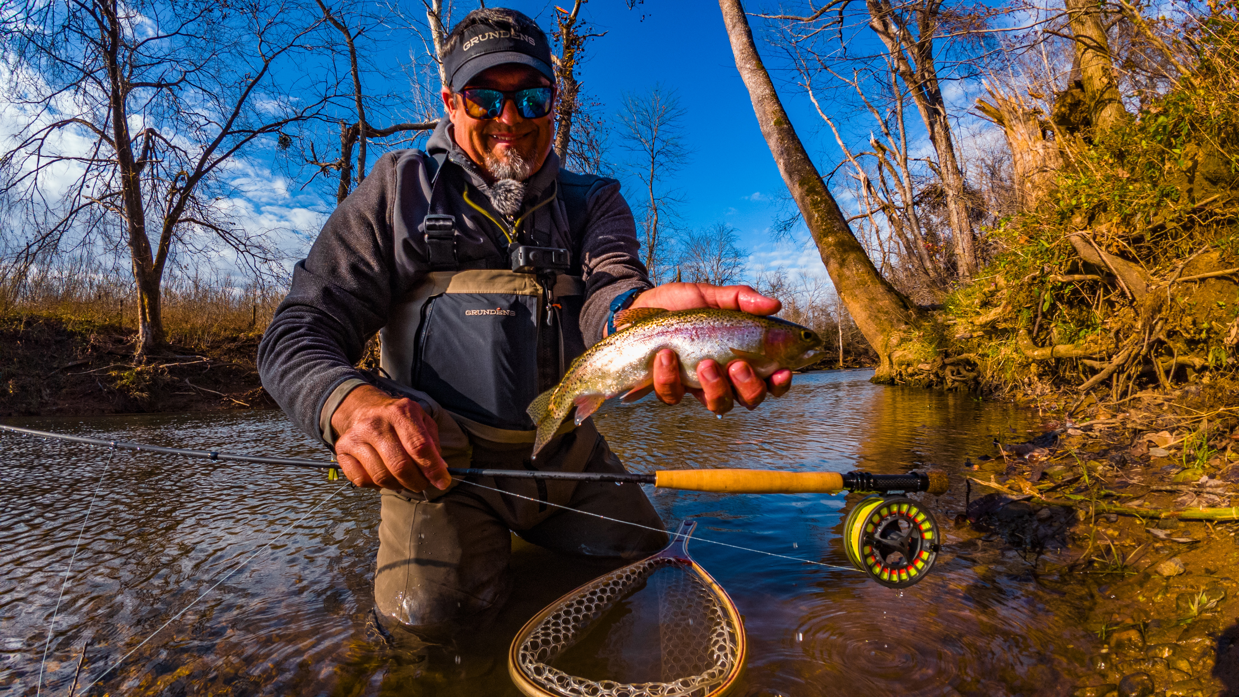 Angler wading a small creek targeting trout along a current seam