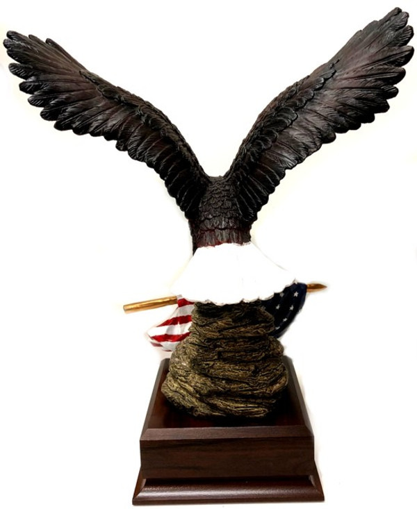 Eagle with US flag hand painted mounted on a 5-1/2 inches long by 5-1/2 inches wide by 2.0 inches high laminated cherry base with free engraving, 12 inches total height.