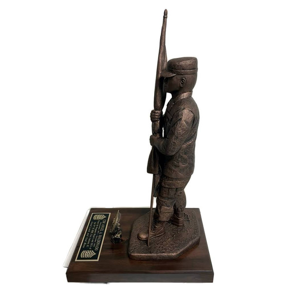 A CSM military statue of "Keeper of the Colors" that is 14 inches tall and wears a patrol cap. It stands on a laminated cherry base that is 8 by 12 by 1.25 inches and has a challenge coin holder and an Army medallion.