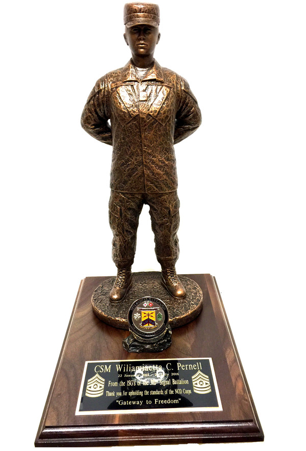 A military statue of a female warrior in patrol cap standing at parade rest, 17 inches tall, on a genuine walnut base of 9 by 12 inches with a holder for a challenge coin. No challenge coin is provided: a medallion of Army, Air Force, Navy or Marine will be included unless otherwise specified.