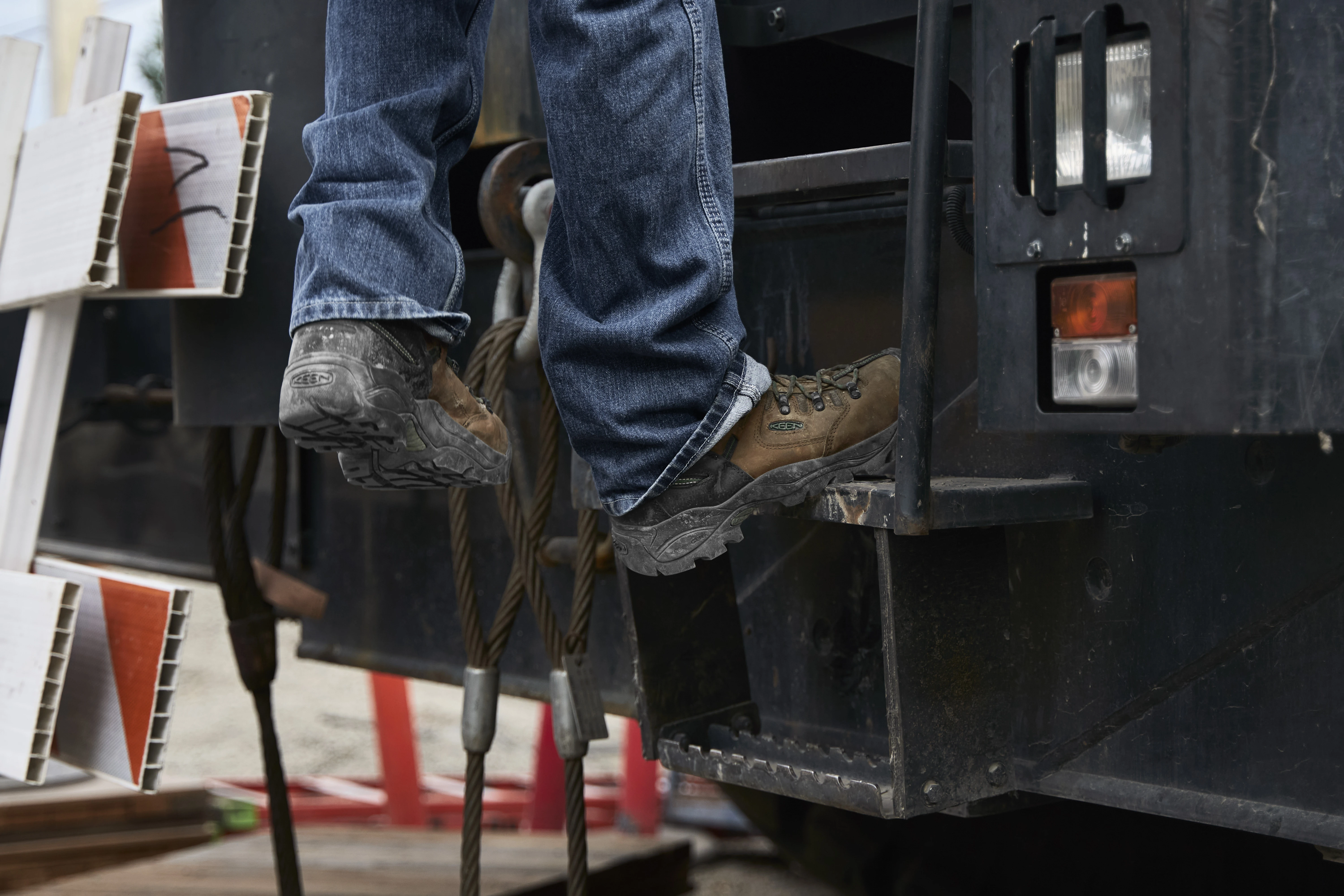 Worker in jeans standing on the back of a utility truck wearing KEEN Utility work boots