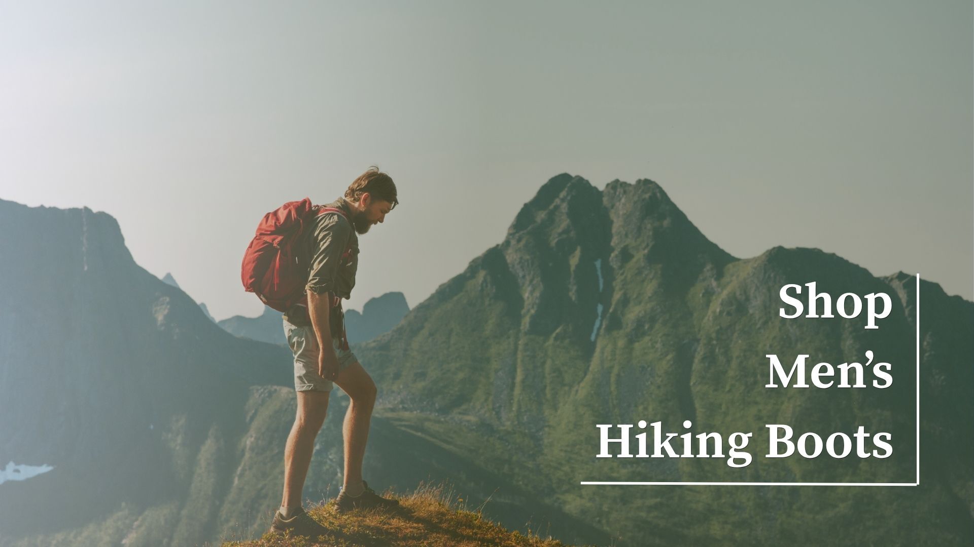 Man hiking through mountains while wearing a backpack, representing men's hiking boots.