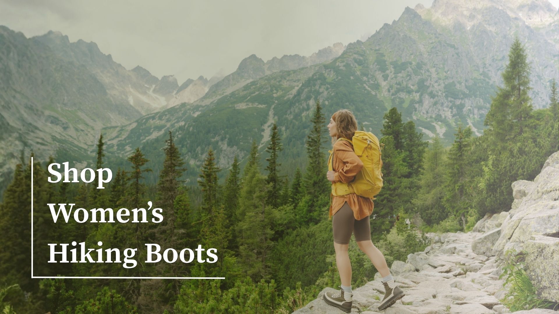 Woman hiking on a mountain trail with a backpack, promoting women's hiking boots.