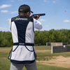 Man in navy and white Nica shooting vest fires shotgun at clay pigeon.