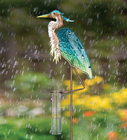 in a garden there is a decorative sculpted heron holding a rain collection tube with gauges for measuring rainfall extending from one of its legs