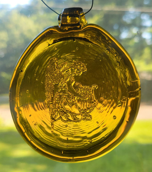 Glass suncatcher, yellow in color, features and angle playing a harp.