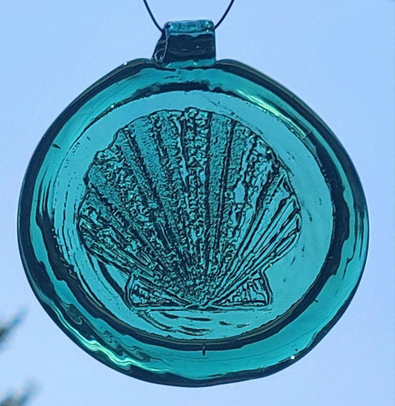 a round green glass sun catcher with relief image of a scallop shell