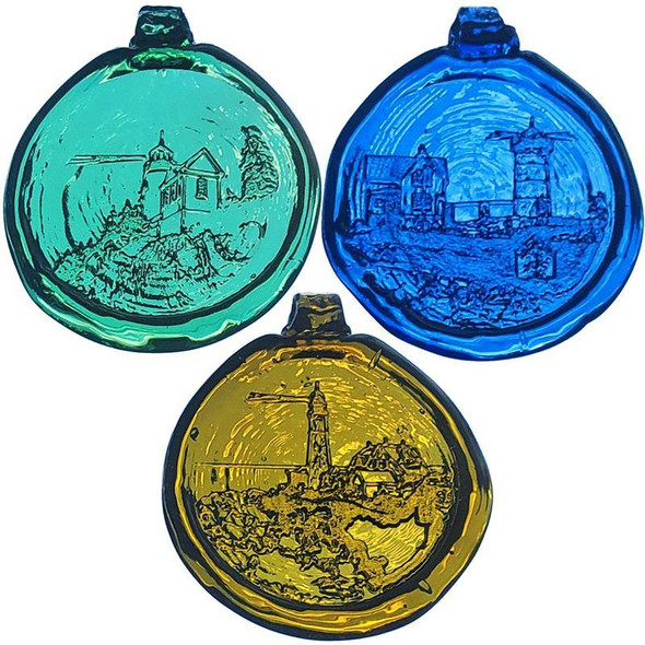 a trio of round, glass suncatchers; a lighthouse on green glass, a lighthouse on blue glass, and a lighthouse on amber yellow glass.