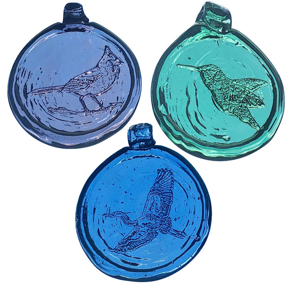 a trio of round glass suncatchers with images of birds; a cardinal, a hummingbird, and a heron