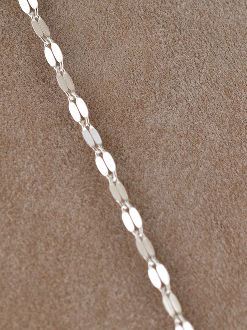 The Valencia Lariat is a striking chain necklace crafted from sterling silver links, designed to float and shimmer on the neckline and decolletage.