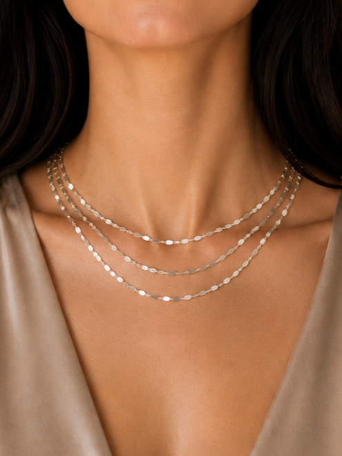 The Valencia Layers Necklace is a striking multi-chain necklace crafted from sterling silver links, designed to float and shimmer on the neckline.