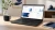 Modern Windows laptop displaying abstract document, spreadsheet, presentation, email and note-taking panels in a home office