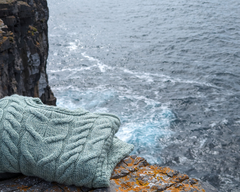 Folded cream Aran knitwear resting on island stone