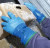 Blue PVC work gloves handling a container with ice