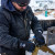 Worker wearing waterproof insulated work gloves while handling metal equipment on a snowy outdoor jobsite