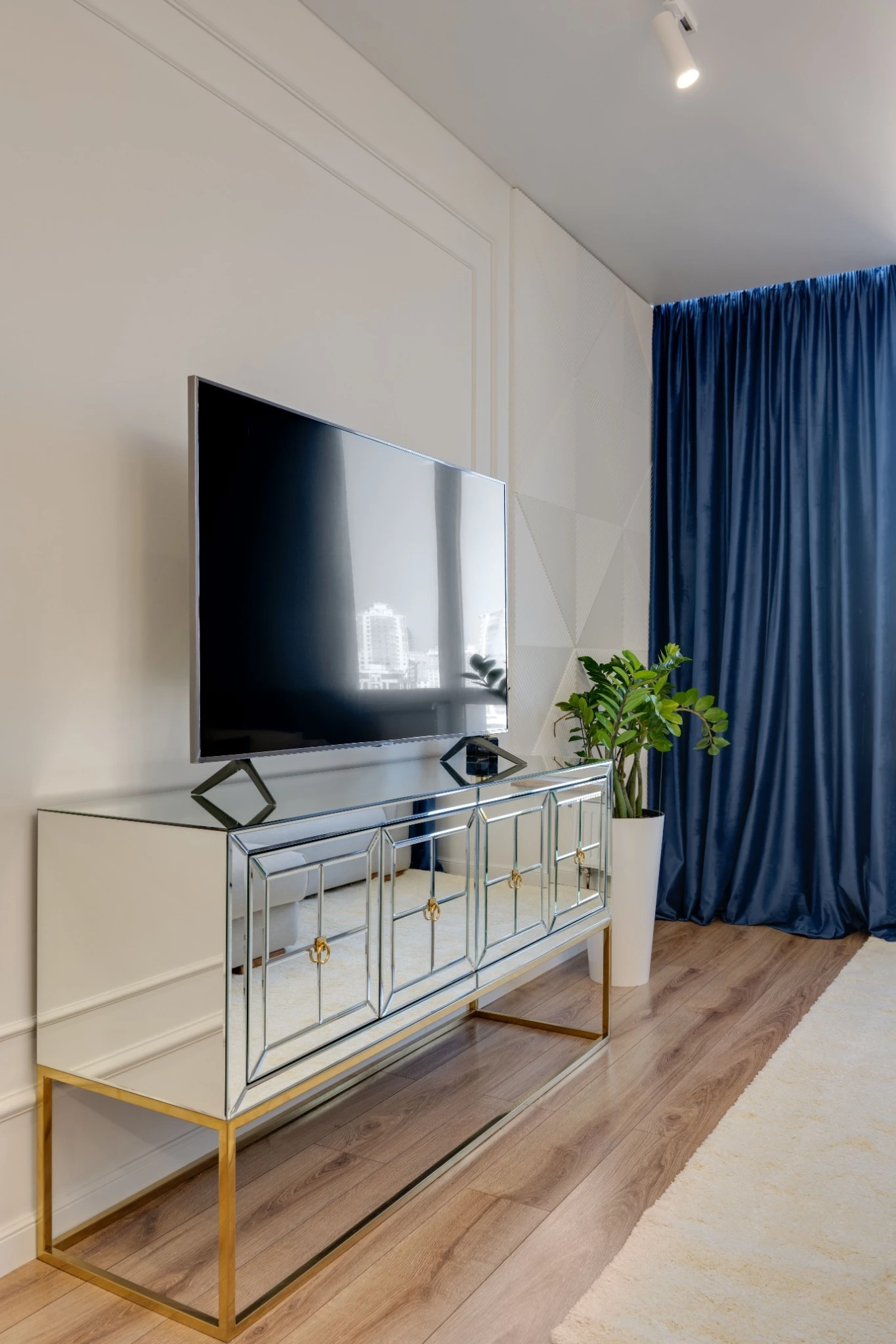 Large television on a console beside blue curtains in a modern living room