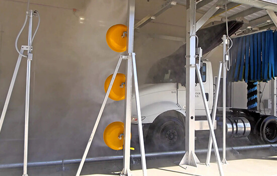Tractor-trailer rig passing through an automated large vehicle wash system.