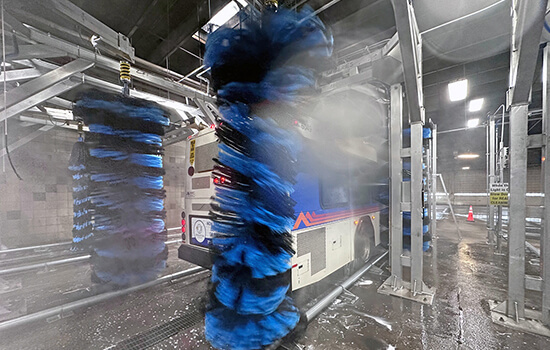 Transit bus going through commercial vehicle wash system.