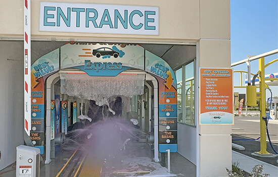 White SUV going through a retail car wash.