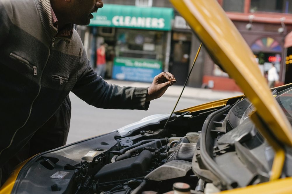 a man reaching toward a hood lift to remove it