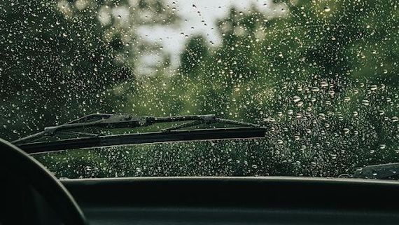 an inside view of a car windshield wiper in the rain