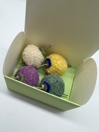 Image shows a green "treasure chest" style paper box holding 4 wool pom pom toys for cats.  Cute kitty gift made in the USA.  