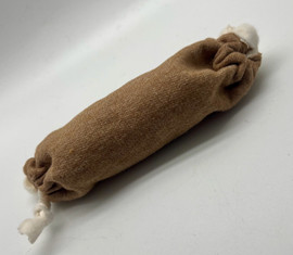 The image shows a brown cat toy on a grey background. The toy is 6 inches long. The toy is in the shaped of a sausage and has white ties on the ends. There is a brown tag on one end.