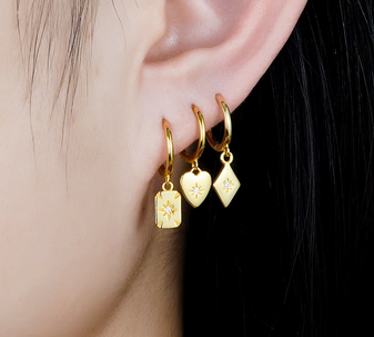 A model wearing a pair of Geo Mosaic Drop Earrings made from 18k gold-filled sterling silver, featuring a geometric mosaic design and Moissanite stones.