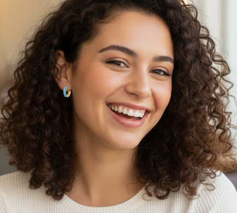 A model wearing bold and sparkling Edgy Sparks Huggies earrings in funky blue with a shiny epoxy finish.