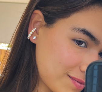 Model wearing the White Whisper Ear Cuff, showcasing its 18K gold-plated design with white enamel stripes.